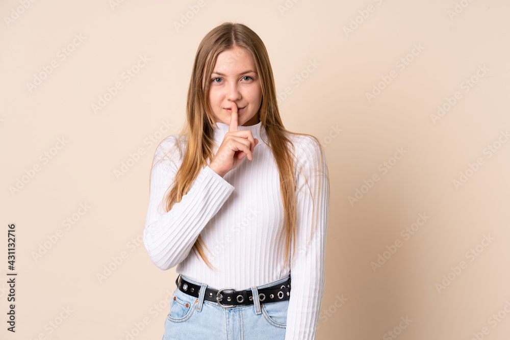 Teenager Ukrainian girl isolated on beige background showing a sign of silence gesture putting finger in mouth Teenager Ukrainian girl isolated on beige background showing a sign of silence gesture putting finger in mouth