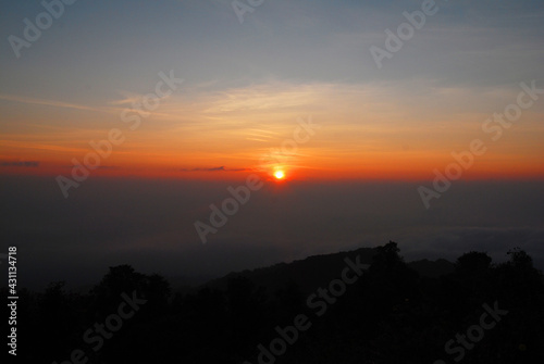 Landscape Tranquil scene of the sunrise with Orange sky and fog around the mountain in the morning at doi pha hom pok national park Thailand.