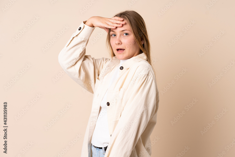 Teenager Ukrainian girl isolated on beige background doing surprise gesture while looking to the side Teenager Ukrainian girl isolated on beige background doing surprise gesture while looking to the side