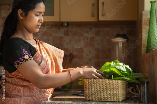 A young woman segregating her home grown vegetables in the kitchen	 photo