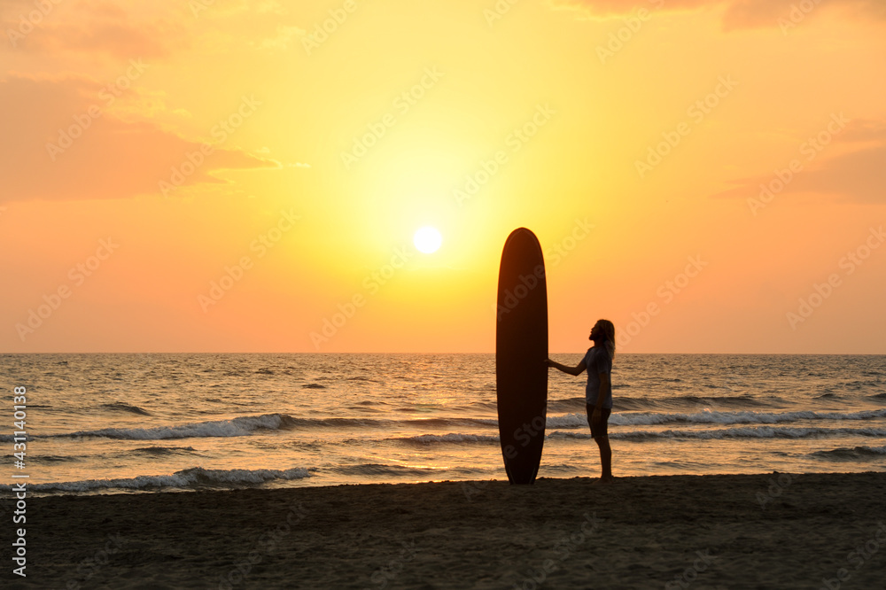 Surfista al tramonto guarda il mare della Versilia.

