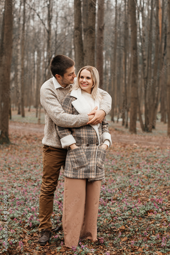 A young, loving couple have fun walking in nature in the rain.