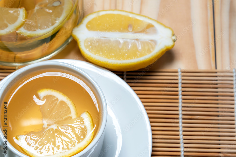 Fresh honey mixed with fresh lemon juice and hot water in white cup and jar for drink .Lemon slices in a cup and plate Fresh honey mixed with fresh lemon juice and hot water in white cup and jar for drink .Lemon slices in a cup and plate