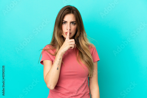 Young caucasian woman isolated on blue background showing a sign of silence gesture putting finger in mouth