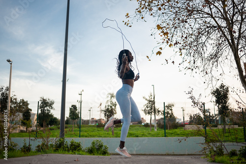 profile view of a black woman jumping rope on the street. Outdoor exercise, fitness routine