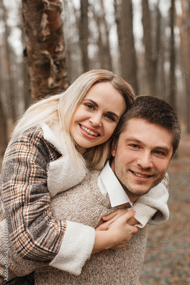 A young, loving couple have fun walking in nature in the rain.