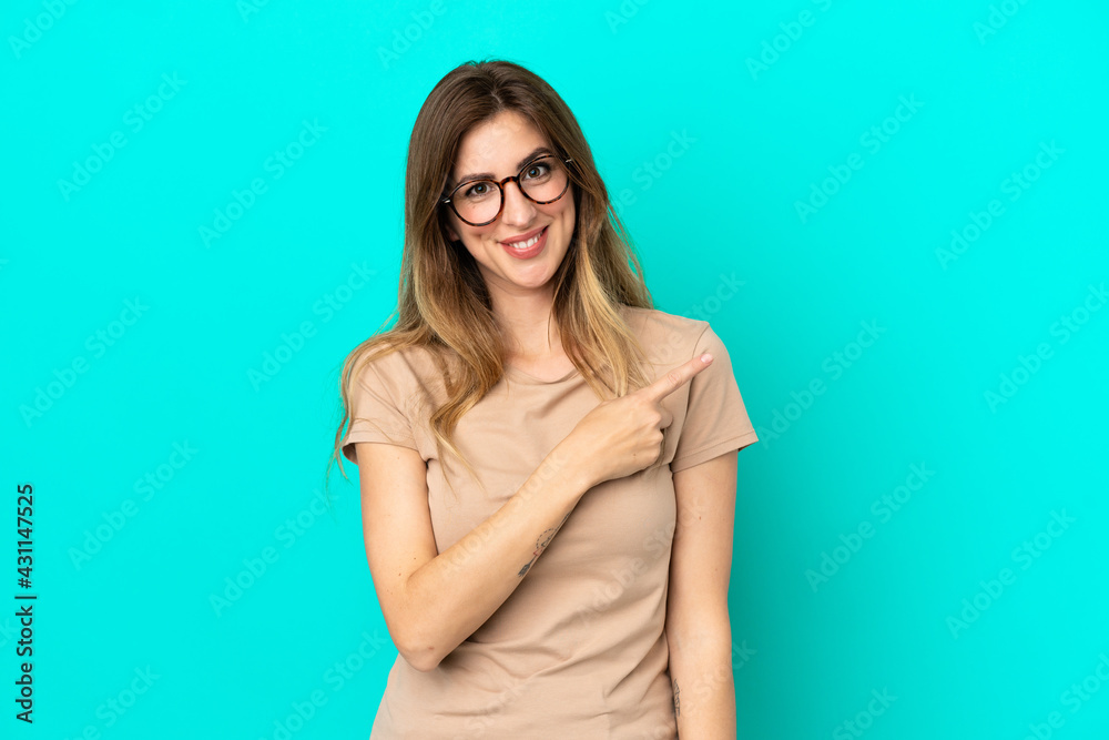 Obraz premium Young caucasian woman isolated on blue background pointing to the side to present a product