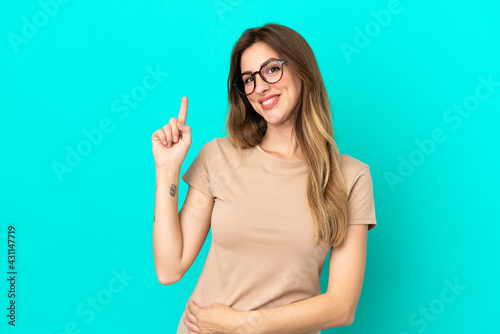 Young caucasian woman isolated on blue background showing and lifting a finger in sign of the best