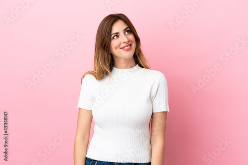 Caucasian woman isolated on pink background thinking an idea while looking up © luismolinero