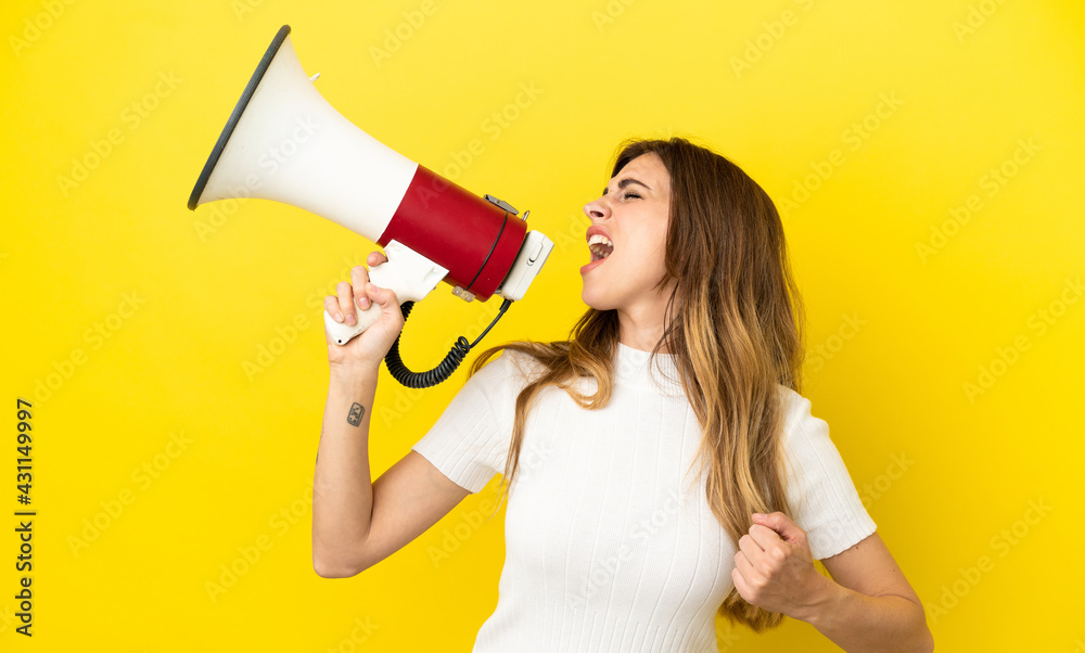 Caucasian woman isolated on yellow background shouting through a megaphone to announce something in lateral position Caucasian woman isolated on yellow background shouting through a megaphone to announce something in lateral position