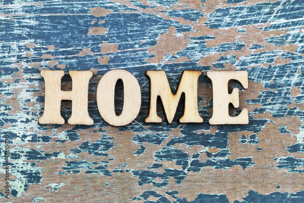 Word home written with colorful wooden letters on rustic wooden surface and colorful flowers