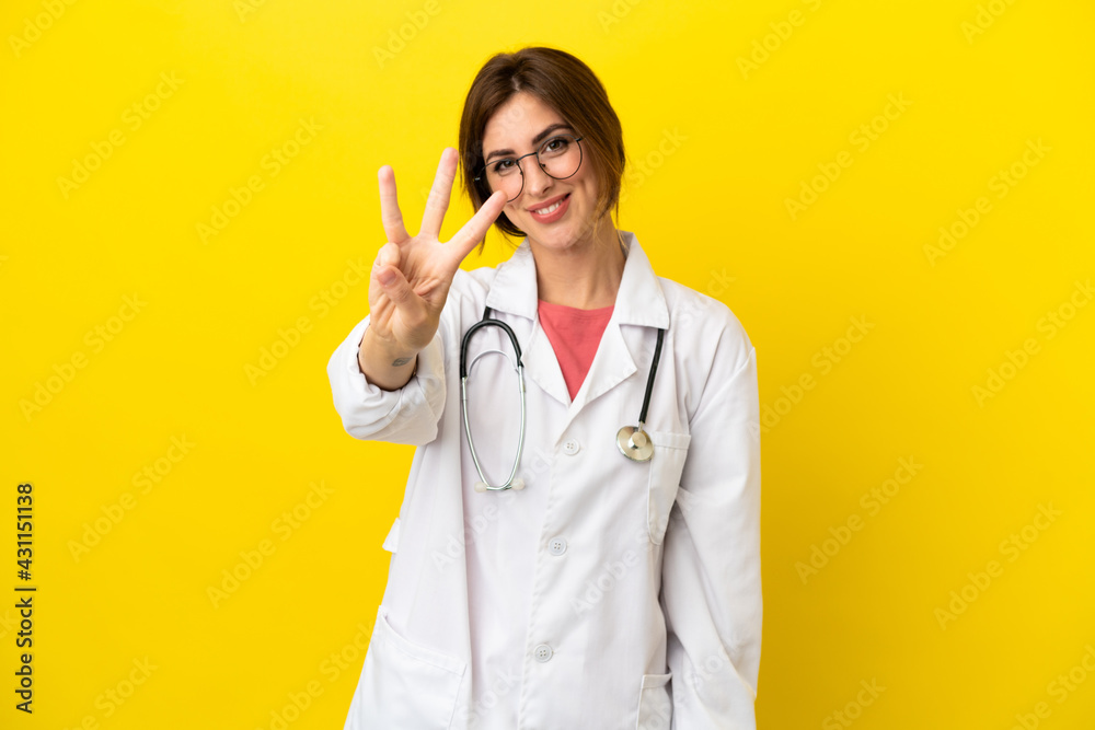 Doctor woman isolated on yellow background happy and counting three with fingers Doctor woman isolated on yellow background happy and counting three with fingers