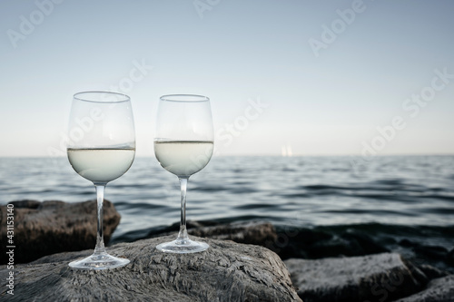 Two wine glasses set on a stone. Sea view