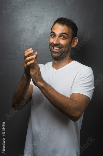 Man wearing a white tshirt over a grey background cheering up photo