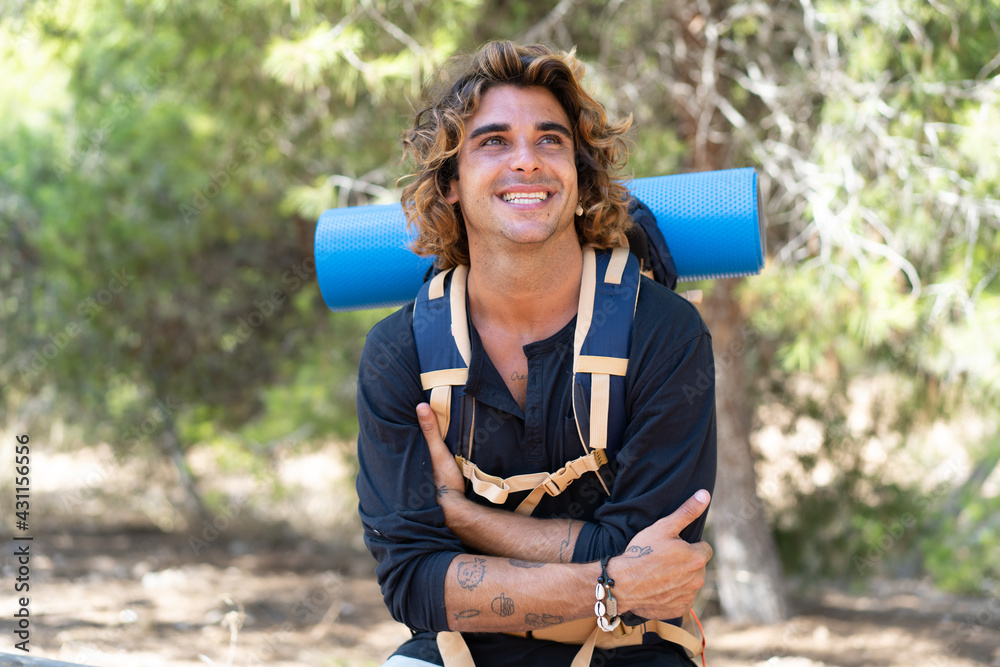 Mountaineer man with a big backpack at outdoors looking up while smiling Mountaineer man with a big backpack at outdoors looking up while smiling