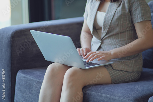 Closeup of woman sitting on sofa and using laptop computer