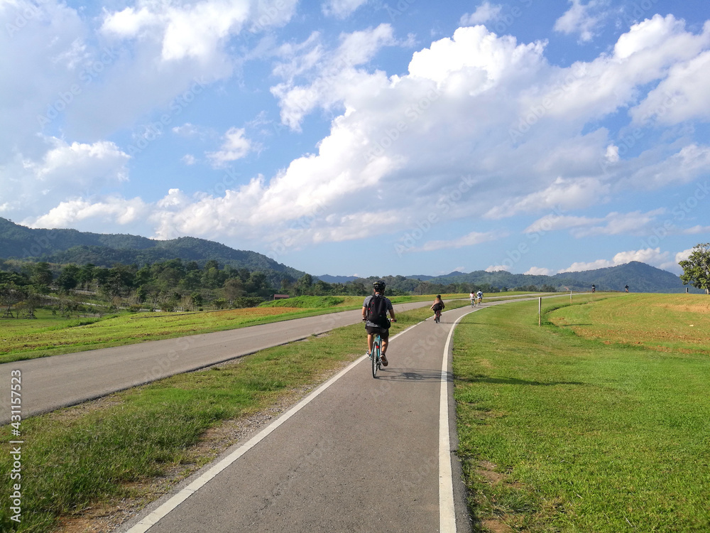Obraz premium Sport activity ride bicycle on bicycle lane in the parks with Cloud blue sky at singha park , chiang rai , thailand - Travel park and Outdoor