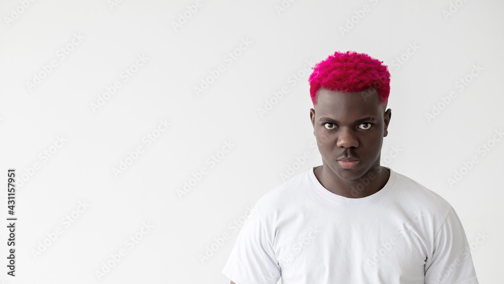 Angry black man. Masculine power. Stress mind. Negative thoughts. Advertising background. Brutal african guy with bright pink hair t-shirt looking at camera isolated white copy space. Angry black man. Masculine power. Stress mind. Negative thoughts. Advertising background. Brutal african guy with bright pink hair t-shirt looking at camera isolated white copy space.