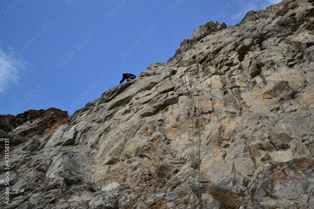 A rock climber in a white helmet climbs a rock in sunny weather A rock climber in a white helmet climbs a rock in sunny weather