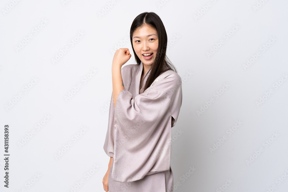 Young Chinese girl wearing kimono over isolated background celebrating a victory Young Chinese girl wearing kimono over isolated background celebrating a victory