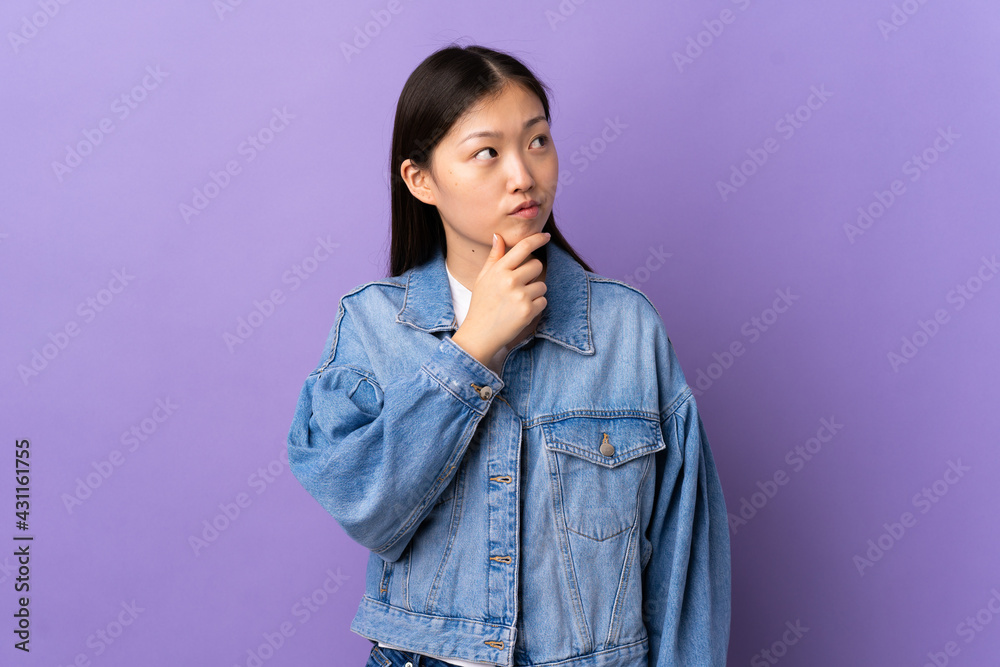 Young Chinese girl over isolated purple background having doubts Young Chinese girl over isolated purple background having doubts