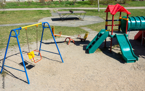 Colorful plastic children's playground with slides and ladders and swings on the playground in the yard