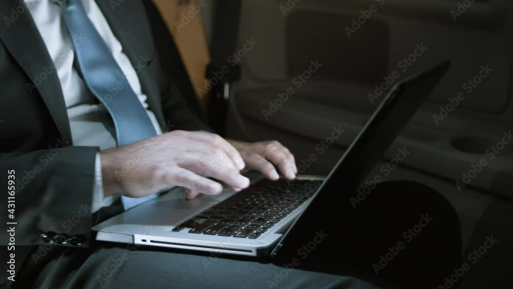 Close-up of male hands typing on laptop. Hand os senior man in official suit sitting in moving car and writing emails to partners. Using laptop, technology concept. Close-up of male hands typing on laptop. Hand os senior man in official suit sitting in moving car and writing emails to partners. Using laptop, technology concept.