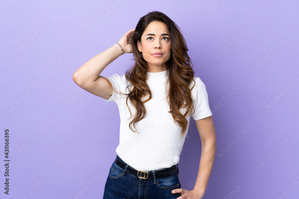 Woman over isolated purple background having doubts Woman over isolated purple background having doubts