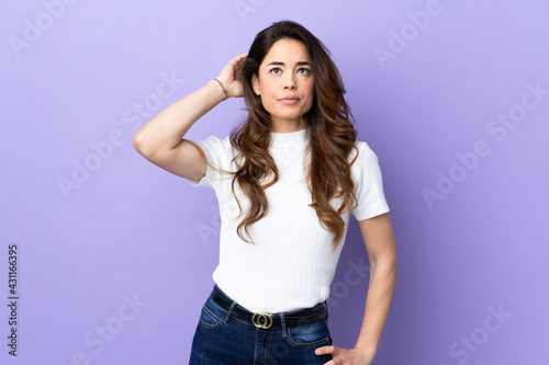 Woman over isolated purple background having doubts