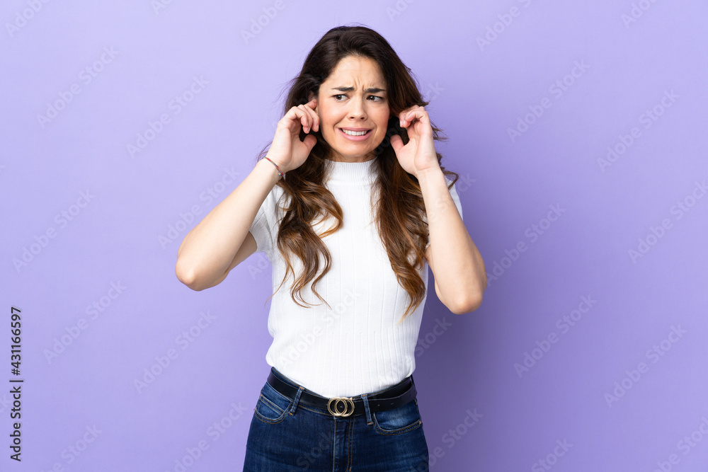 Woman over isolated purple background frustrated and covering ears