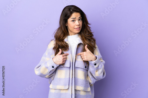Woman over isolated purple background pointing to oneself