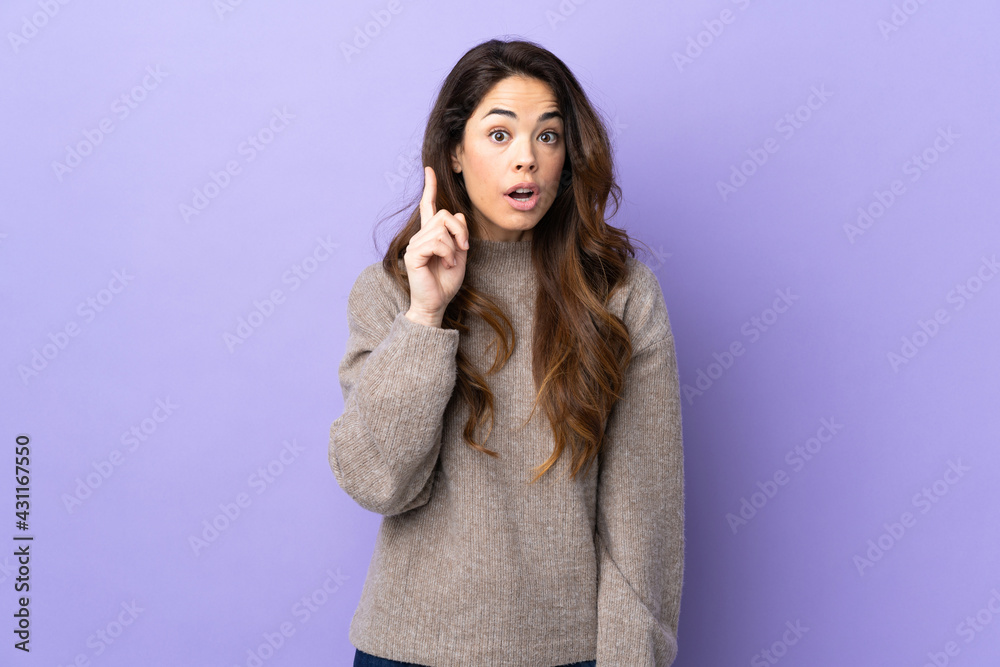 Woman over isolated purple background intending to realizes the solution while lifting a finger up Woman over isolated purple background intending to realizes the solution while lifting a finger up