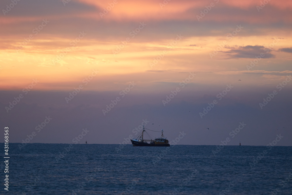 A ship with a colorful sky on the Wadden Sea in the Netherlands