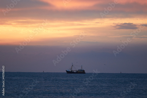 A ship with a colorful sky on the Wadden Sea in the Netherlands