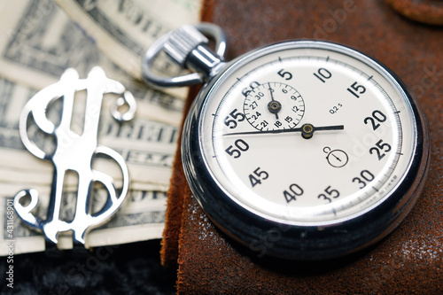Dollar close-up. Money macro shot. The stopwatch lies on paper banknotes and a leather wallet. Clock, watch, timepiece, timer, clock face, mechanical device, speedometer 