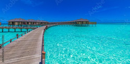 Maldives island, luxury water villas resort and wooden pier. Beautiful sky and ocean lagoon beach background. Summer vacation holiday travel concept. Paradise luxury scene, stunning landscape panorama
