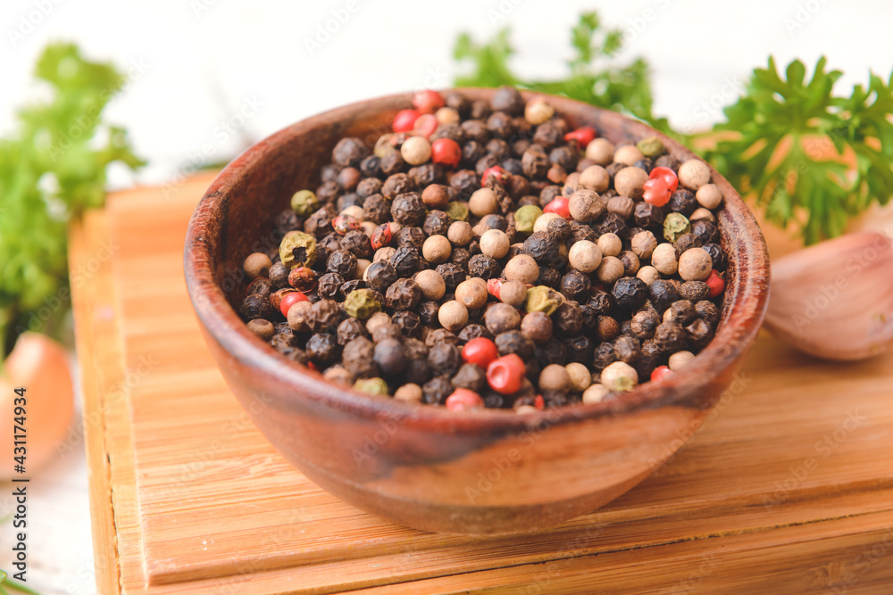 Bowl with peppercorns on light wooden background Bowl with peppercorns on light wooden background