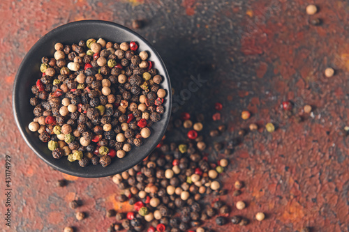Bowl with peppercorns on grunge background