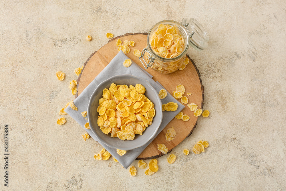 Bowl and jar with tasty cornflakes on light background Bowl and jar with tasty cornflakes on light background