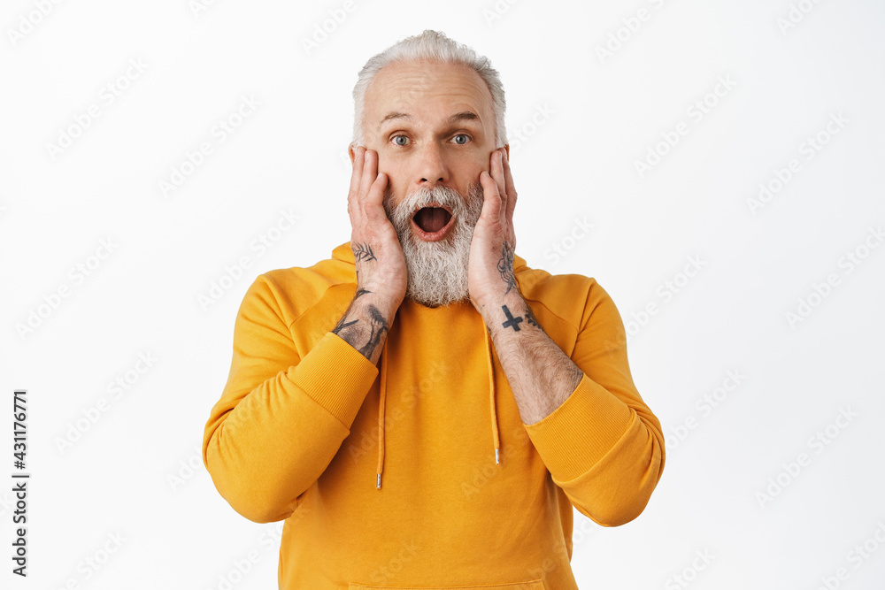 Omg amazing. Impressed senior guy with tattoos, hipster old man drop jaw, gasping and saying wow, look amazed and surprised at advertisement, awesome announcement, white background Omg amazing. Impressed senior guy with tattoos, hipster old man drop jaw, gasping and saying wow, look amazed and surprised at advertisement, awesome announcement, white background
