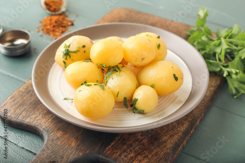 Tablou pe pânză Plate of tasty boiled potatoes with parsley on color wooden background