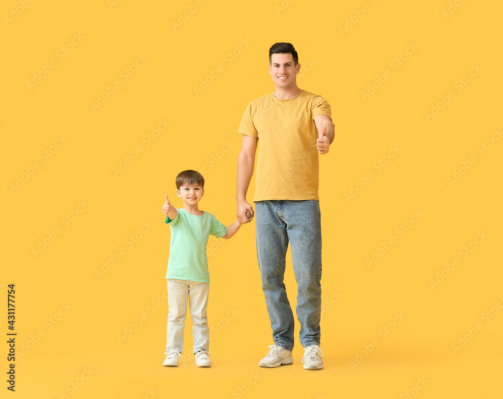 Happy father and his little son showing thumb-up on color background Happy father and his little son showing thumb-up on color background