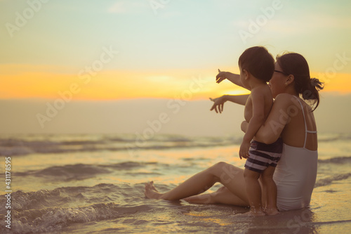 Obraz na płótnie Happy family resting at beach in summer, Mother and som feet at the sea foam at the sunlight water is moving w salonie