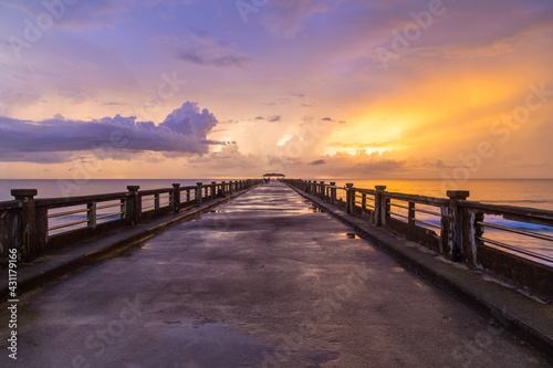 Bridge on beach in sunset and sea wave.