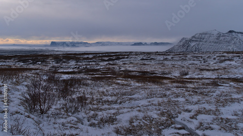 Beautiful view over the rugged and snow-covered Skaftafell mountains in southern Iceland with majestic Vatnajökull glacier in background on cloudy winter day.