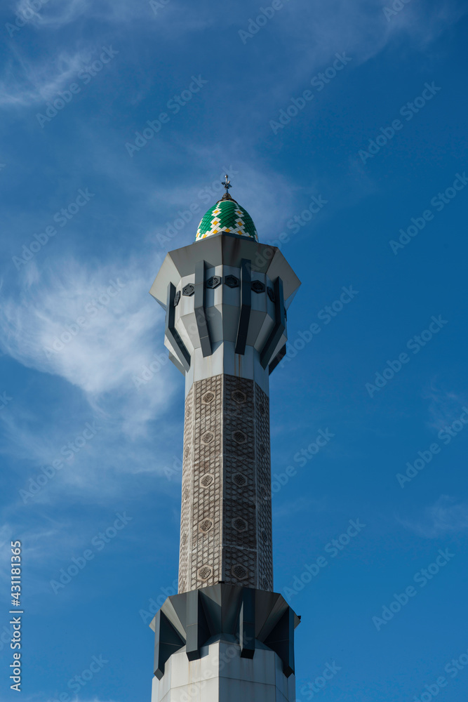 
The tower of a mosque that appears to stand very high into the blue sky.