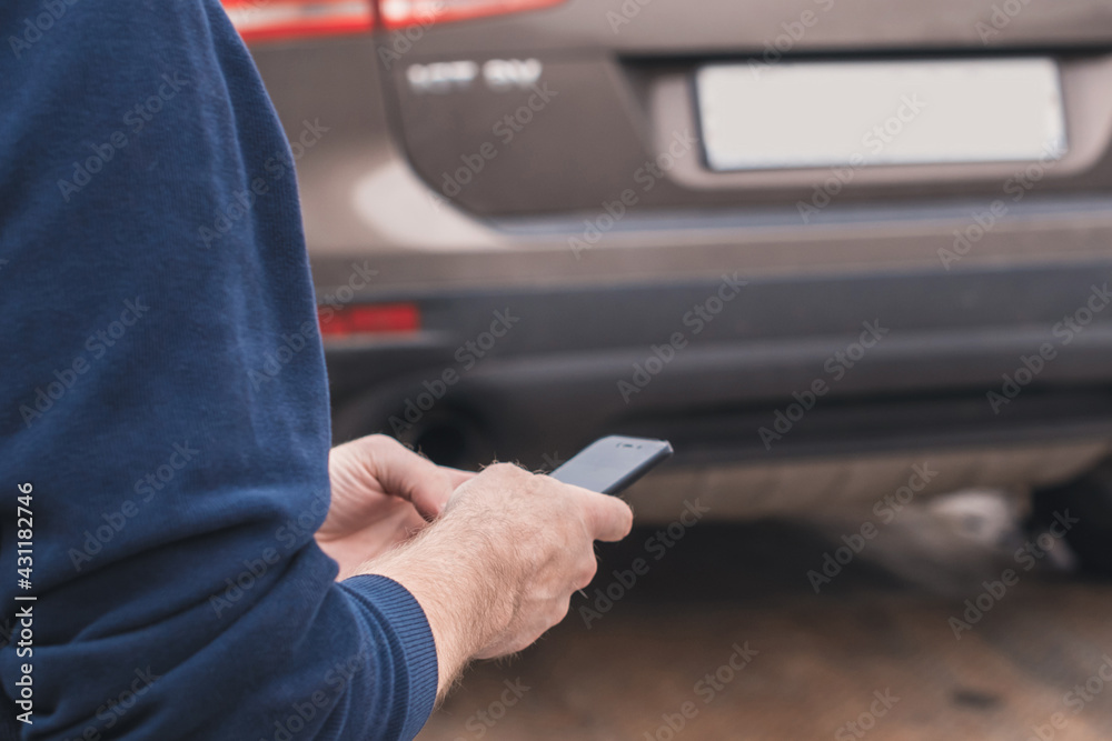 Man with mobile phone.Tow truck with worker towing a broken down car on the highway. Selective focus. Concept Man with mobile phone.Tow truck with worker towing a broken down car on the highway. Selective focus. Concept