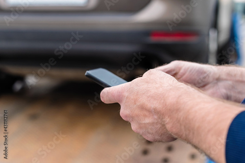 Man with mobile phone.Tow truck with worker towing a broken down car on the highway. Selective focus. Concept