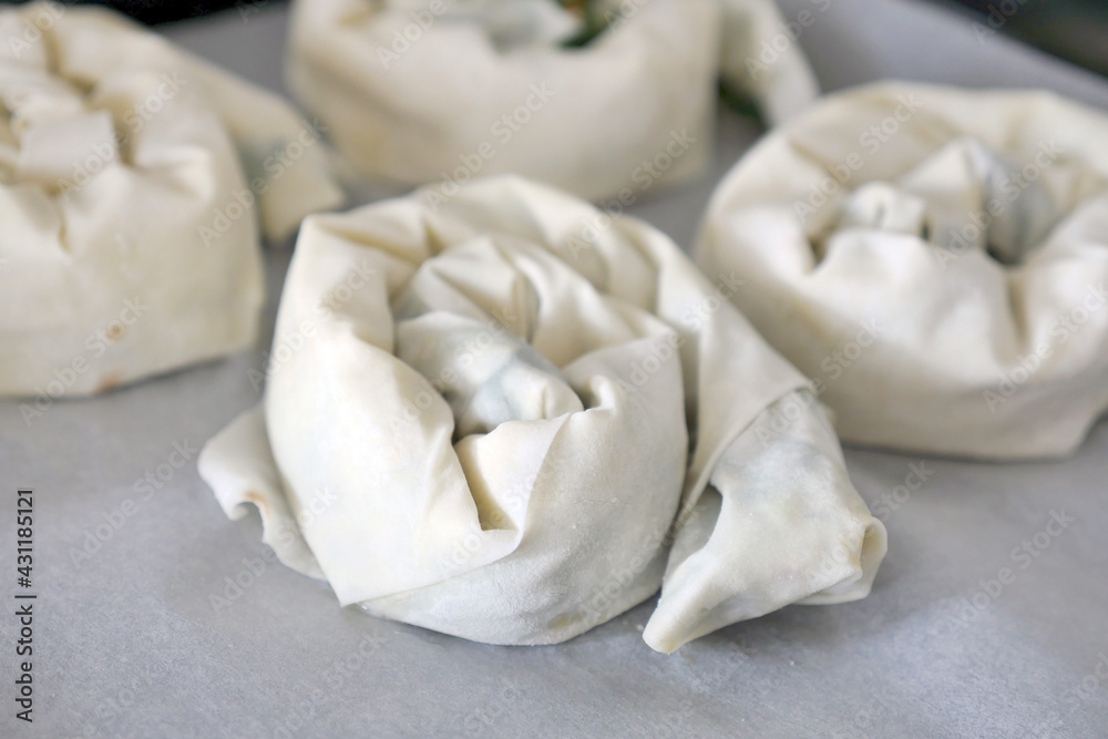 A woman making spinach and cheese pastry with thin dough, A woman making spinach and cheese pastry with thin dough,