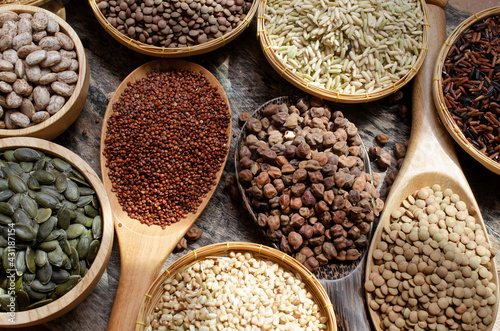 Dry organic brown chick pea with rice, red quinoa, lentils, pinto, pumpkin seeds, and buckwheat in wooden spoon on grunge background in dark tone under morning sun light